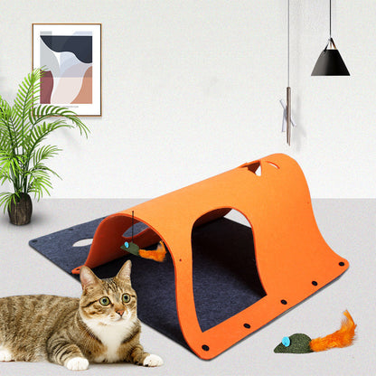 An orange tunnel toy made of felt, with a cat sitting beside it and a toy mouse attached to one end.